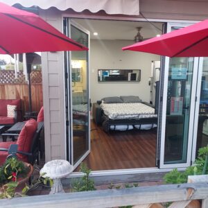 A bed sitting on top of a patio next to two umbrellas.