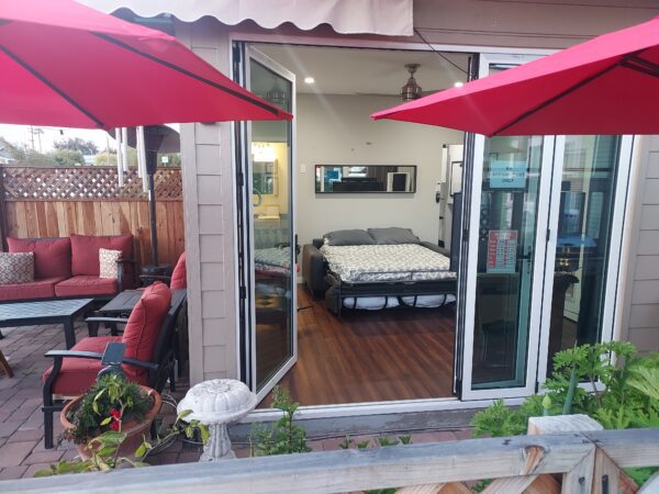 A bed sitting on top of a patio next to two umbrellas.