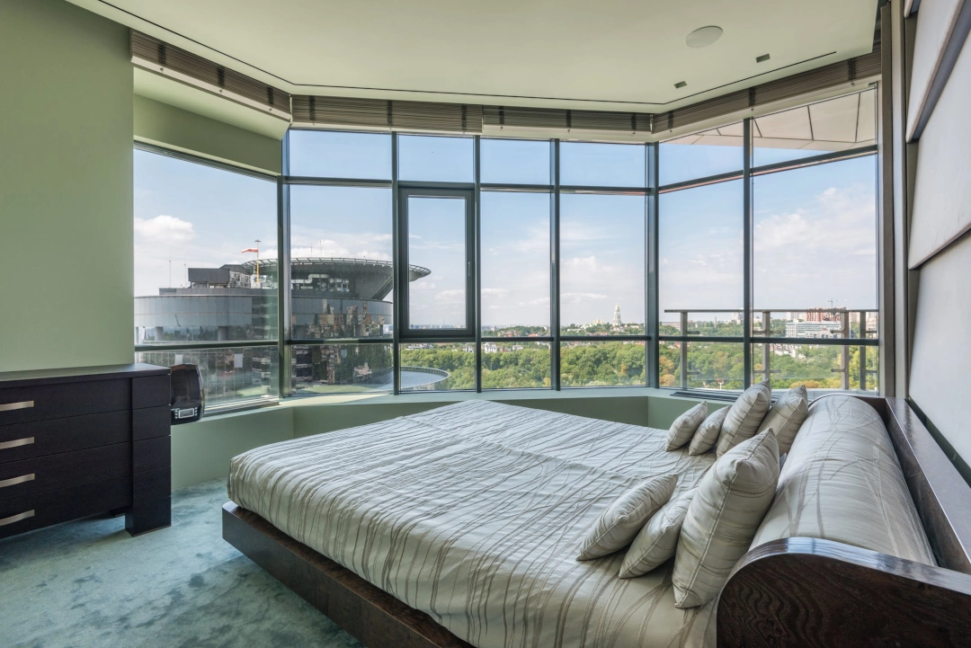 A large bed in the middle of a room with windows.