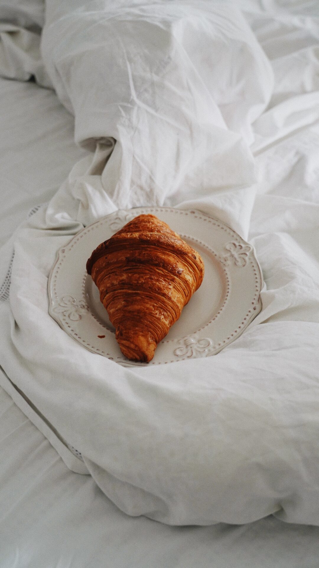 A croissant on top of a white plate.