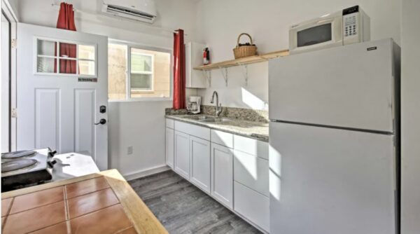 A kitchen with white cabinets and wooden floors.