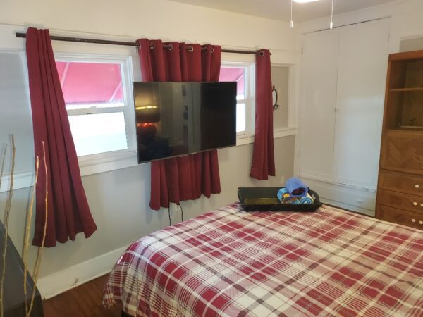 A bedroom with a bed and television on the wall.