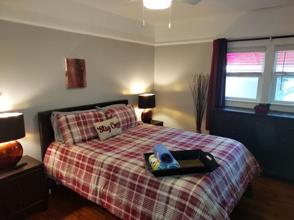 A bed room with a red plaid bedspread and a tray of food.