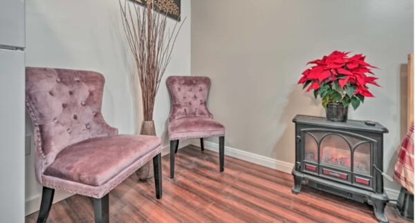 A living room with two pink chairs and a fireplace.