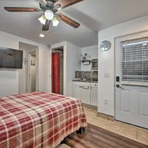 A bedroom with a bed, tv and kitchen.