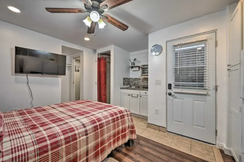 A bedroom with a bed, tv and kitchen.