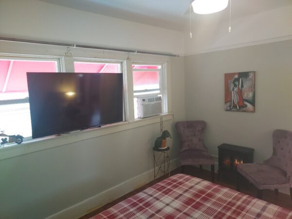 A bedroom with a bed, chair and television.