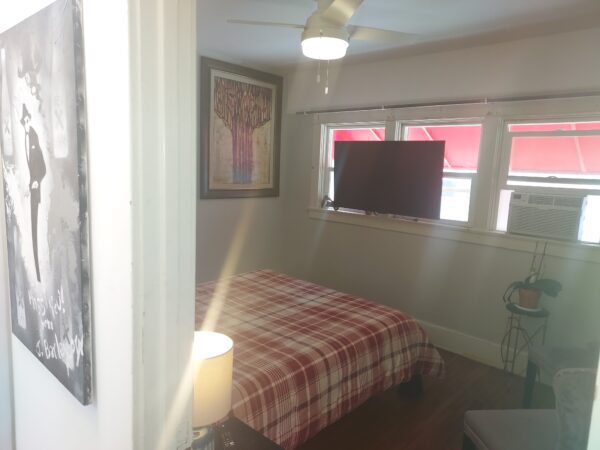 A bedroom with a bed, tv and window.