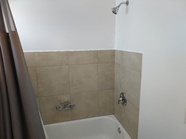 A bathroom with a tub and shower head.