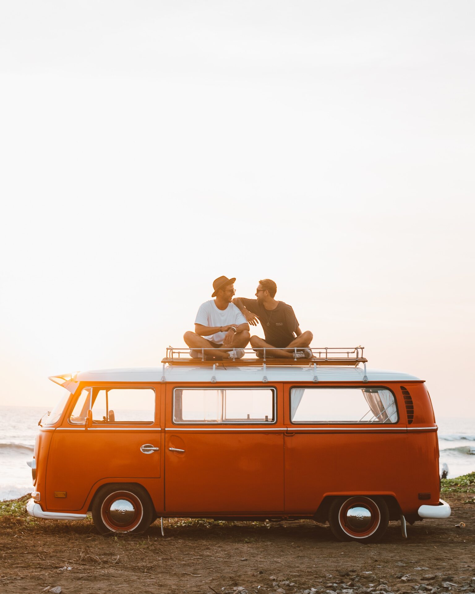 Two people sitting on the roof of a van.