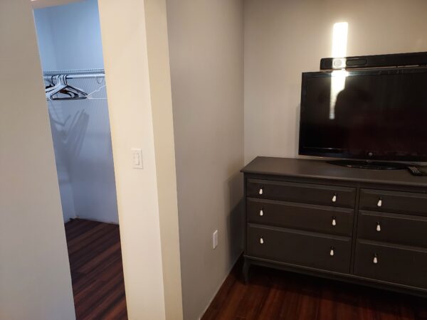 A dresser with a television in it next to a walk-in shower.