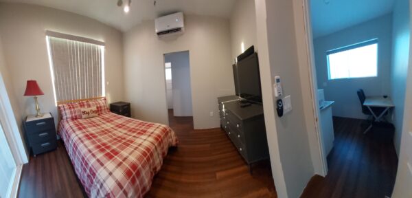 A bedroom with a bed, dresser and television.