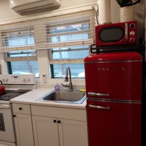 A red refrigerator and microwave in a kitchen.