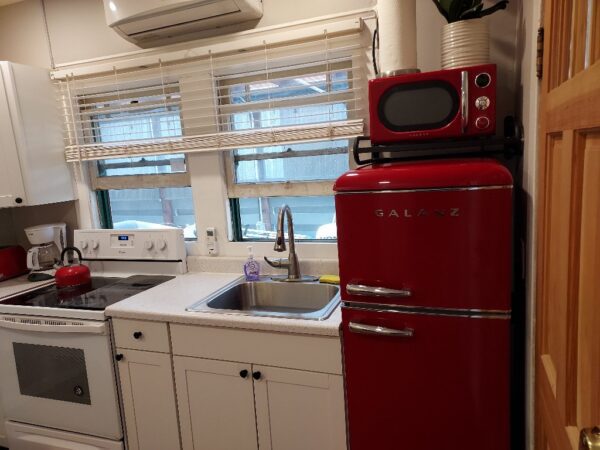 A red refrigerator and microwave in a kitchen.