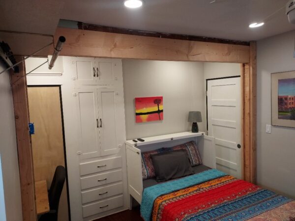 A bedroom with a bed, closet and desk.