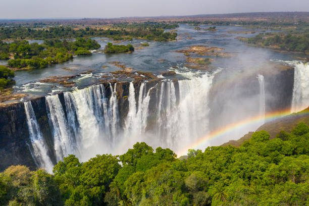 Livingstone Victoria Falls2 Aerial few of the world famous Victoria Falls with a large rainbow over the falls. This is right at the border between Zambia and Zimbabwe in Southern Africa. The mighty Victoria Falls at Zambezi river are one of the most visited touristic places in Africa.