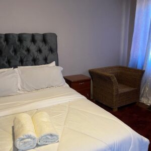 Cozy bedroom with a neatly made bed and two rolled towels.