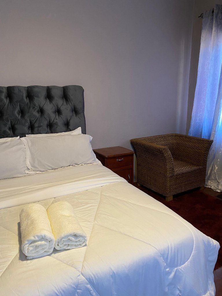 Cozy bedroom with a neatly made bed and two rolled towels.